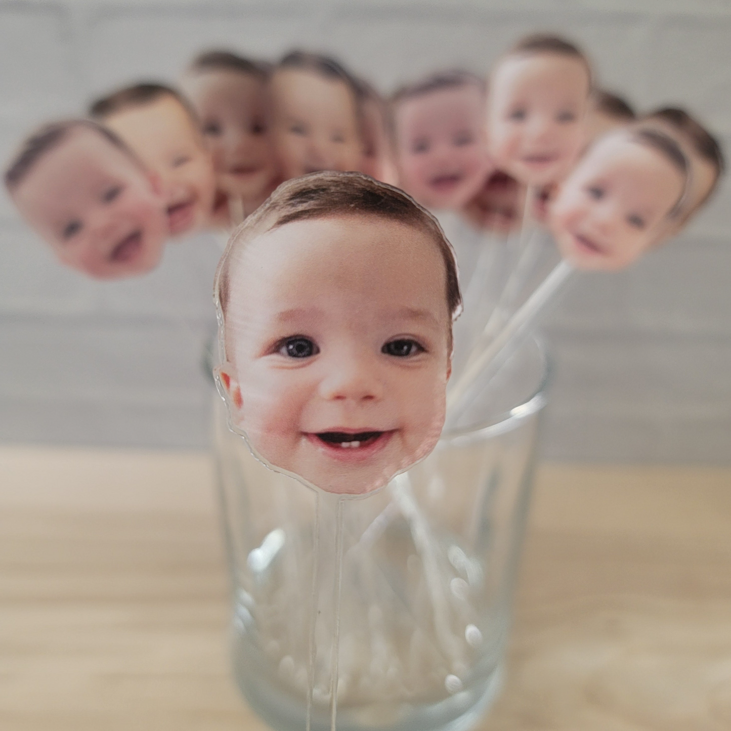 Clear drink stirrer with the face of a baby printed at the top of the drink stirrer.