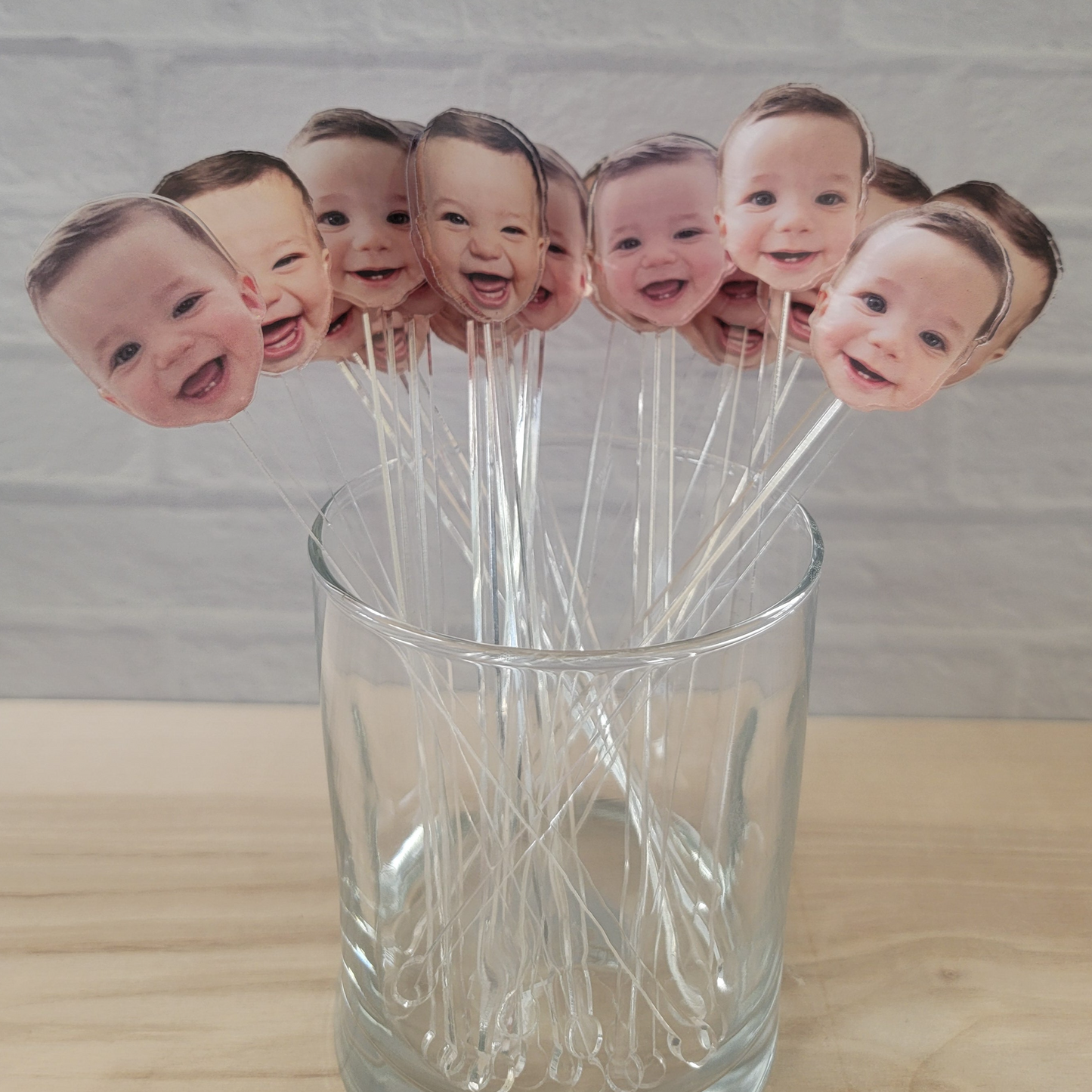 Clear drink stirrer with the face of a baby printed at the top of the drink stirrer.